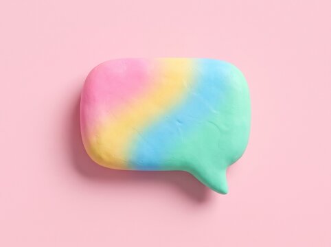 Colorful rainbow speech bubble on a soft pastel pink background creative concept