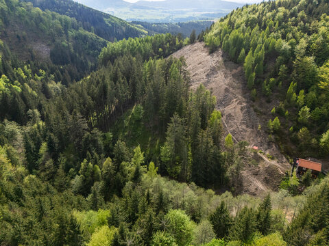 Aerial view of Svatodusna Old copper mine dumps surrounded by dense coniferous forests and lush green hills in Lubietova, Banska Bystrica Regio, Slovakia.