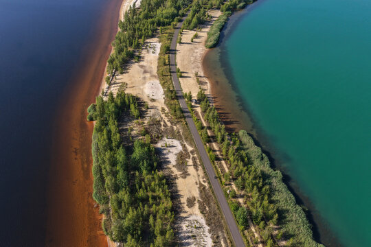 Aerial view of the recultivated open cast coal pits in Leipziger Neuseenland, with a narrow strip of land and road separating two distinct bodies of water in Leipzig, Saxony, Germany.