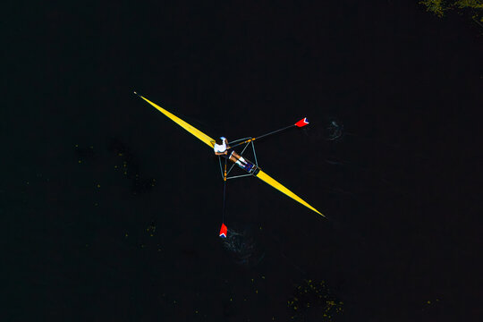 Aerial view of a single rower in a yellow scull on dark water in Poland.