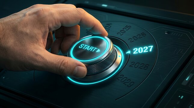 Hand turning a futuristic metal dial with glowing blue light selecting year 2027 start button symbolizing future planning and new beginnings.