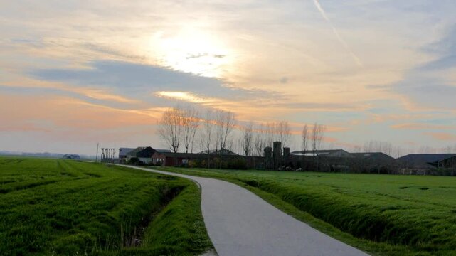 Peaceful Dutch countryside timelapse with a farm, green fields, and a colorful sunset sky.