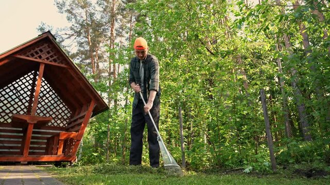 Man rake garden beside wooden swing in backyard