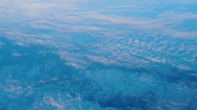 mackerel sky pattern ripples across clouds textured altocumulus formation stretches to horizon window view from airplane cruise altitude soft daylight open sky vista no land visible below