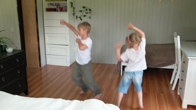 Happy active siblings exercising dancing together. Cute brother and sister jumping, doing fun sports routine. Fighting sedentary lifestyle in kids. Children physical health, energy wellness concept.
