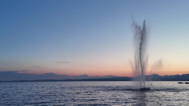 Bardolino, Italy - May 17, 2026 - Serene lake fountain at dusk with wooden pier and distant mountains