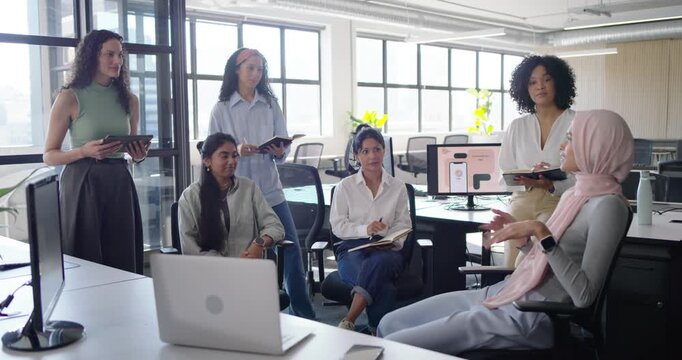 Diverse female coworkers following speaker starting presentation, discussing mockup in open office