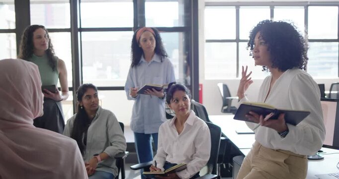 Diverse team at office listening while African American woman on right presenting notes, copy space