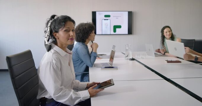 Diverse women meeting room lead pointing app screen Indian woman holding tablet smiling, copy space
