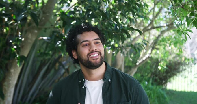 African American man in green shirt smiling and laughing under leafy tree at off-camera voice