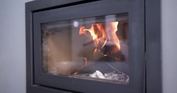 Built-in wood-burning stove is showing embers igniting log, causing flames to curl behind glass