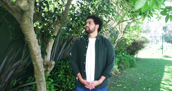African American man by tree, responding to zoom, turning to face camera, wearing green shirt