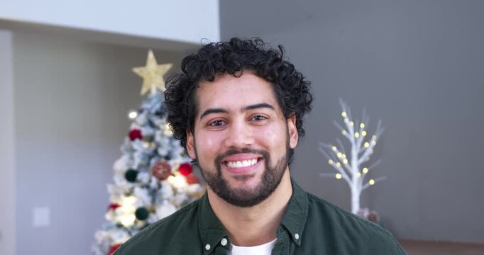 African American man responding to camera gaze, softening and smiling at home near Christmas tree