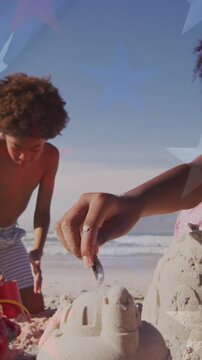 Animation of flag of usa and stars over african american children playing at beach