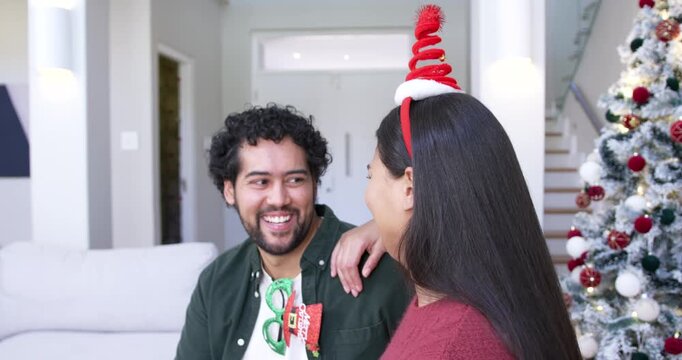African American couple on couch, woman resting hand making man laugh, sharing warmth by tree