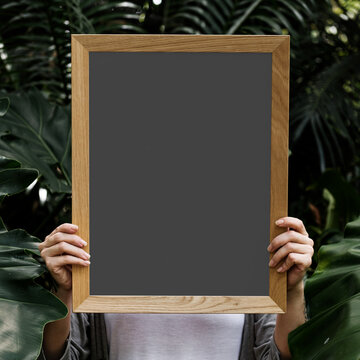 Blank chalkboard amidst lush greenery, suitable as mockup