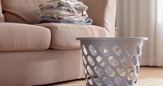 Camera starting rightward tilt is revealing white basket and folded clothes on sofa showing stack