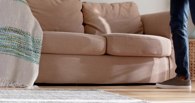 Person entering right holding gray basket, lowering to sofa seat while placing clothes