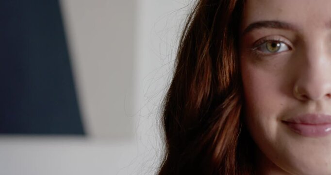 Woman blinking opening eyes smiling as camera focus meeting gaze in room with nose-ring, copy space