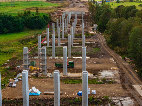 Aerial view of the construction site at Lezky featuring rows of concrete pillars for a new bridge, with a green truck and materials in Lubenec, Usti nad Labem Region, Czechia.