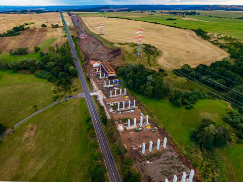 Aerial view of the highway construction site featuring bridge pillars near Lezky, surrounded by agricultural fields and power lines in Lubenec, Usti nad Labem Region, Czechia.