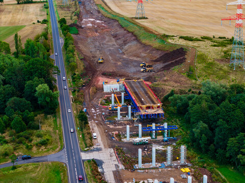 Aerial view of the bridge construction site at Lezky featuring heavy machinery, concrete pillars, and ongoing road infrastructure development near Lubenec, Usti nad Labem Region, Czechia.