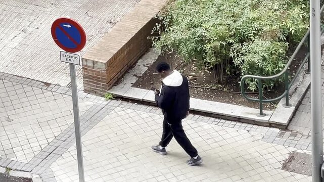 Inmigrante negro con tel&eacute;fono m&oacute;vil persona de color black man immigrant foreign caminando con smartphone africano con celular andando en calle