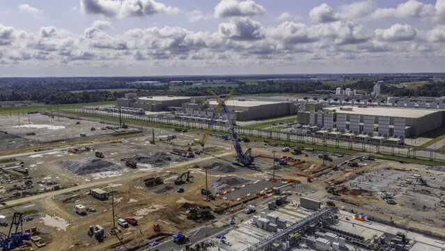 Aerial view of the construction site for a data center extension, featuring heavy machinery, cranes, and earthworks under a cloudy sky in Clarksville, Tennessee, United States.