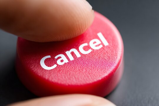 Extreme close-up of a finger pressing a red cancel button. Macro shot of a hand pushing a key to stop a process. Abort or delete concept on a dark background