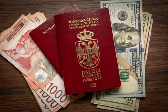 Serbian passport placed between Serbian dinar and US dollar banknotes, representing international travel, currency exchange and travel expenses.