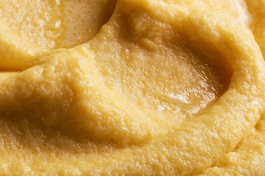 Close view of creamy texture on a spoon with soft yellow spread in a bowl