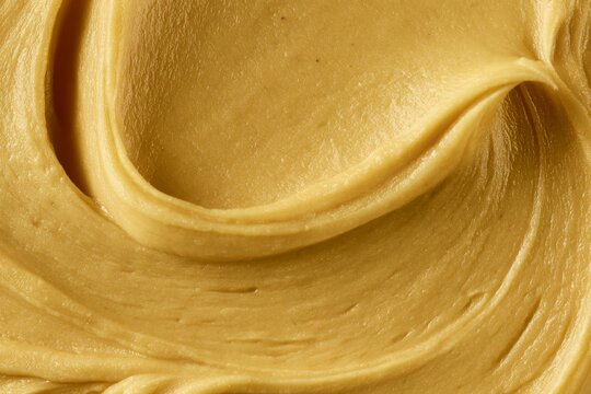 Creamy peanut butter spread on a surface showing texture and color during daytime