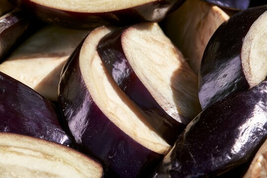 Sliced eggplant pieces arranged closely together on a flat surface in bright light