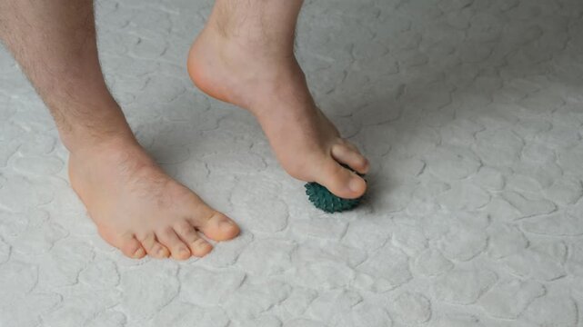 Man massaging myofascial trigger points on foot with green spiky ball