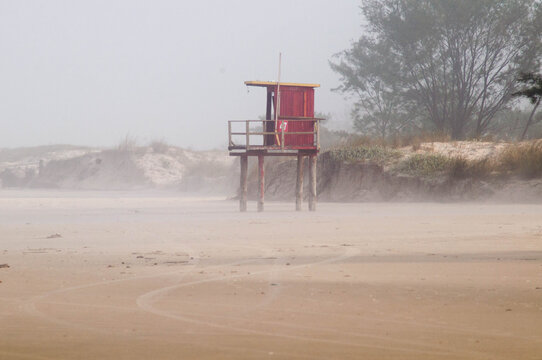 Seaside landscape with red lifeguard tower on sand dune