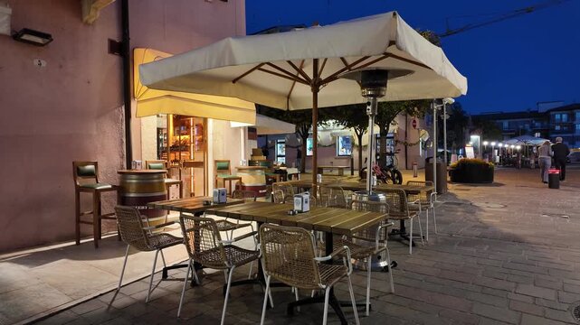 Bardolino, Italy - May 17, 2026 - European outdoor cafe seating at dusk with warm lighting and heaters