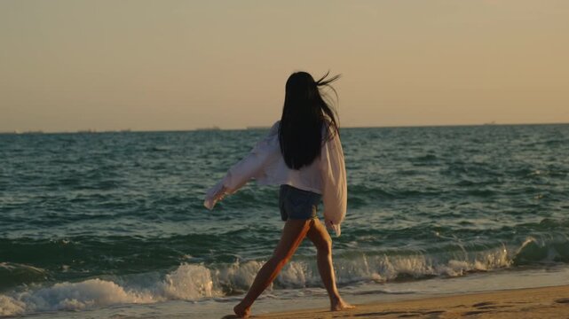 Beautiful beach, woman, walking, sand, closeup views of cheerful girl raising arms during sunset, carefree female traveler enjoying summer vacation on tropical ocean shore.