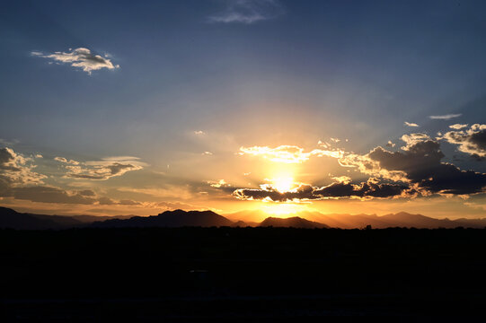 Vibrant orange sunset with sun beams over the mountains near Denver CO