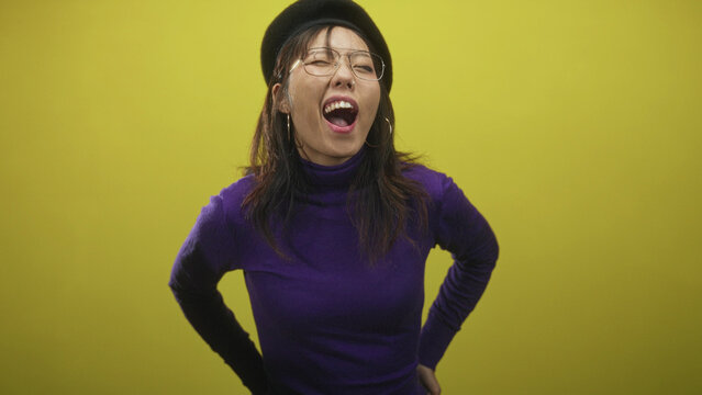 Woman singing with mouth open and hands on hips in studio wearing purple turtleneck and beret; joy spontaneity.