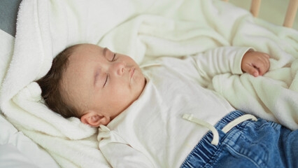 Baby sleeping in cradle on soft blanket, face and small hand visible, fist slightly clenched,...