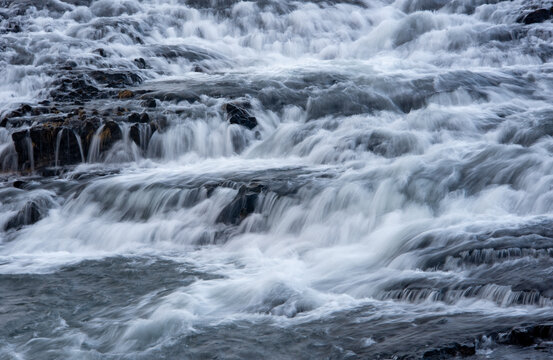 Powerful water surging and cascading over black rocks, showing the strong current of a river in wilderness. Bruarfoss waterfall Golden Circle route Iceland
