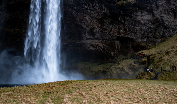Seljalandsfoss Waterfall. People walk hike along the path near the base of the waterfall. Iceland, icelandic landscape