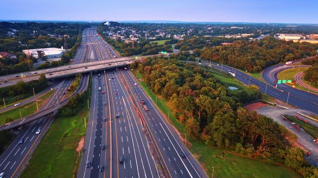 Flyover the lively multi-lane highways along the green roadsides. Middlesex County, New Jersey crossed by the Garden State Parkway at sunset time.