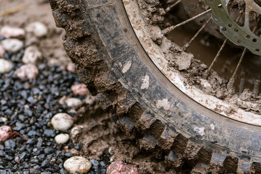 Mud caked knobby tire on gravel with extreme closeup detail