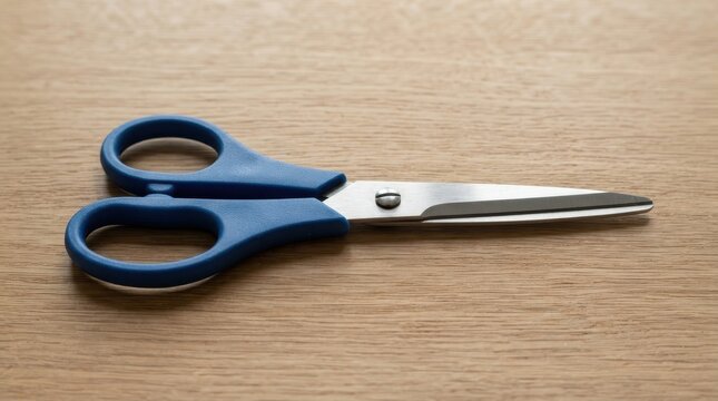 Blue handle scissors on a wooden table surface
