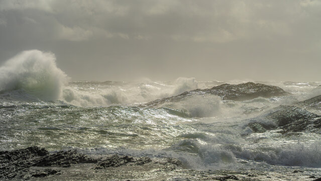Layered wave turbulence fills a rocky North Sea scene near Langesund, Norway, as multiple breakers rise in warm storm light for natural force, marine energy and weather backgrounds.