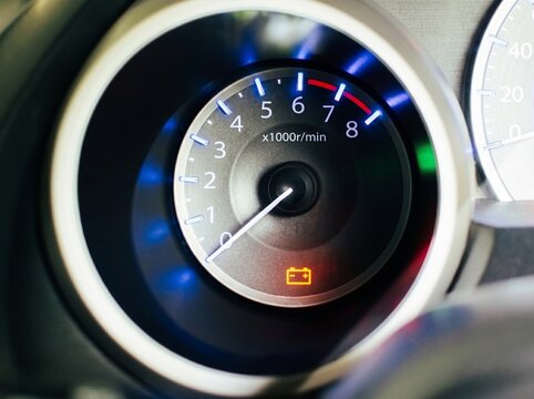 Close Up Of Car Tachometer Gauge Showing RPM And Battery Warning Light On Dashboard