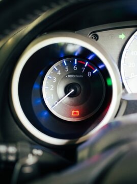 Close Up Of Car Tachometer Gauge Showing RPM And Battery Warning Light On Dashboard