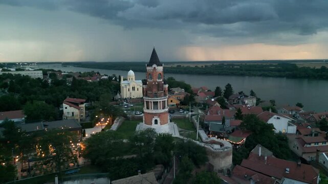 Epic drone shot of Gardos Tower in Zemun with dramatic cloudy sky and lightning striking over the Danube River at dusk, Belgrade, Serbia.