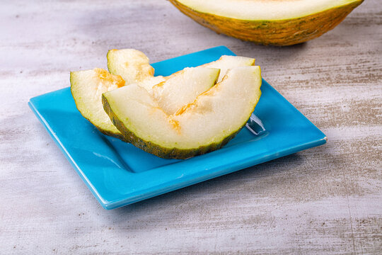 Sliced piel de sapo melon on blue plate with rustic background
